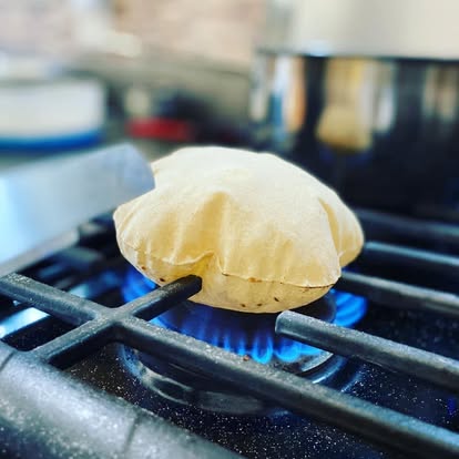 Soft phulka roti puffing up over an open flame